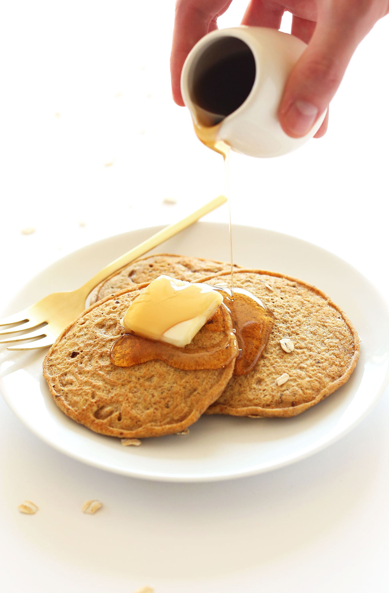 Pouring syrup onto Whole Grain Vegan Pancakes made with spelt flour