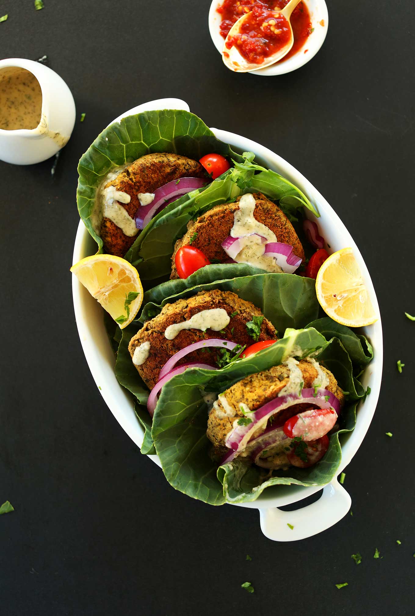 Baking dish filled with falafel burgers stuffed in collard greens with delicious vegetables and sauce