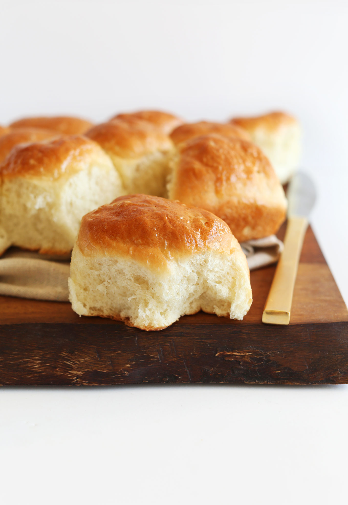Freshly baked Vegan Dinner Rolls resting on a wood cutting board