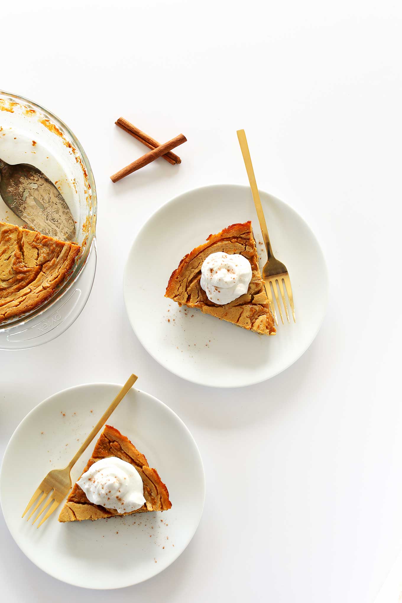 Plates and pie pan filled with amazing vegan pumpkin swirl cheesecake with graham cracker crust