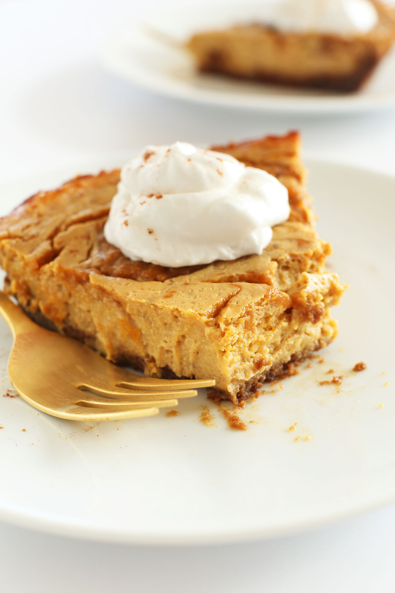 Partially eaten slice of pumpkin swirl cheesecake with coconut whip