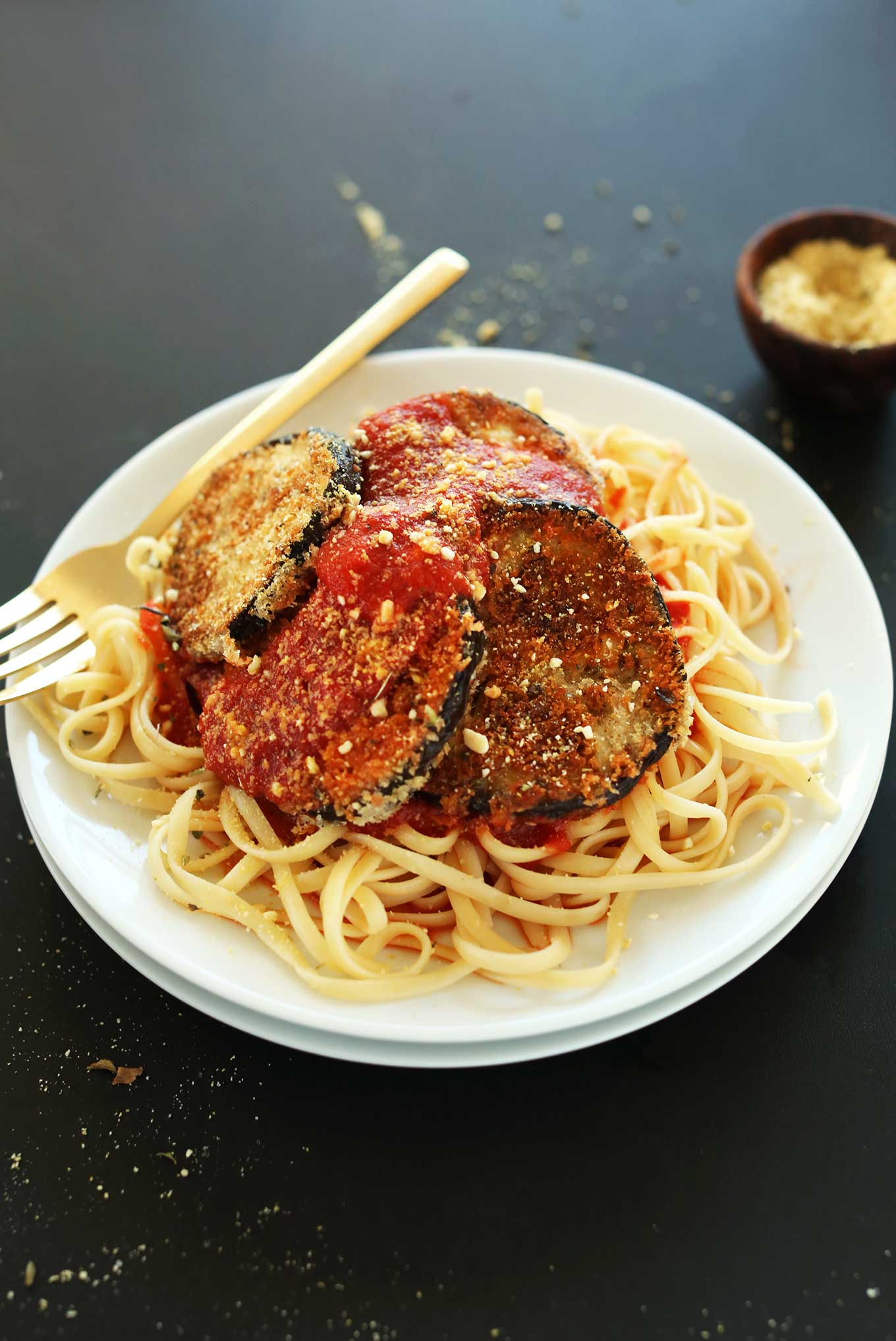 Plate loaded with noodles, marinara, and vegan eggplant parmesan