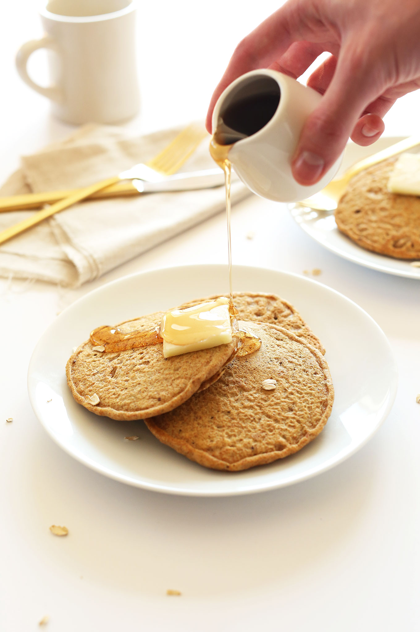 Pouring syrup onto a plate of simple Whole Grain, Healthy Vegan Pancakes
