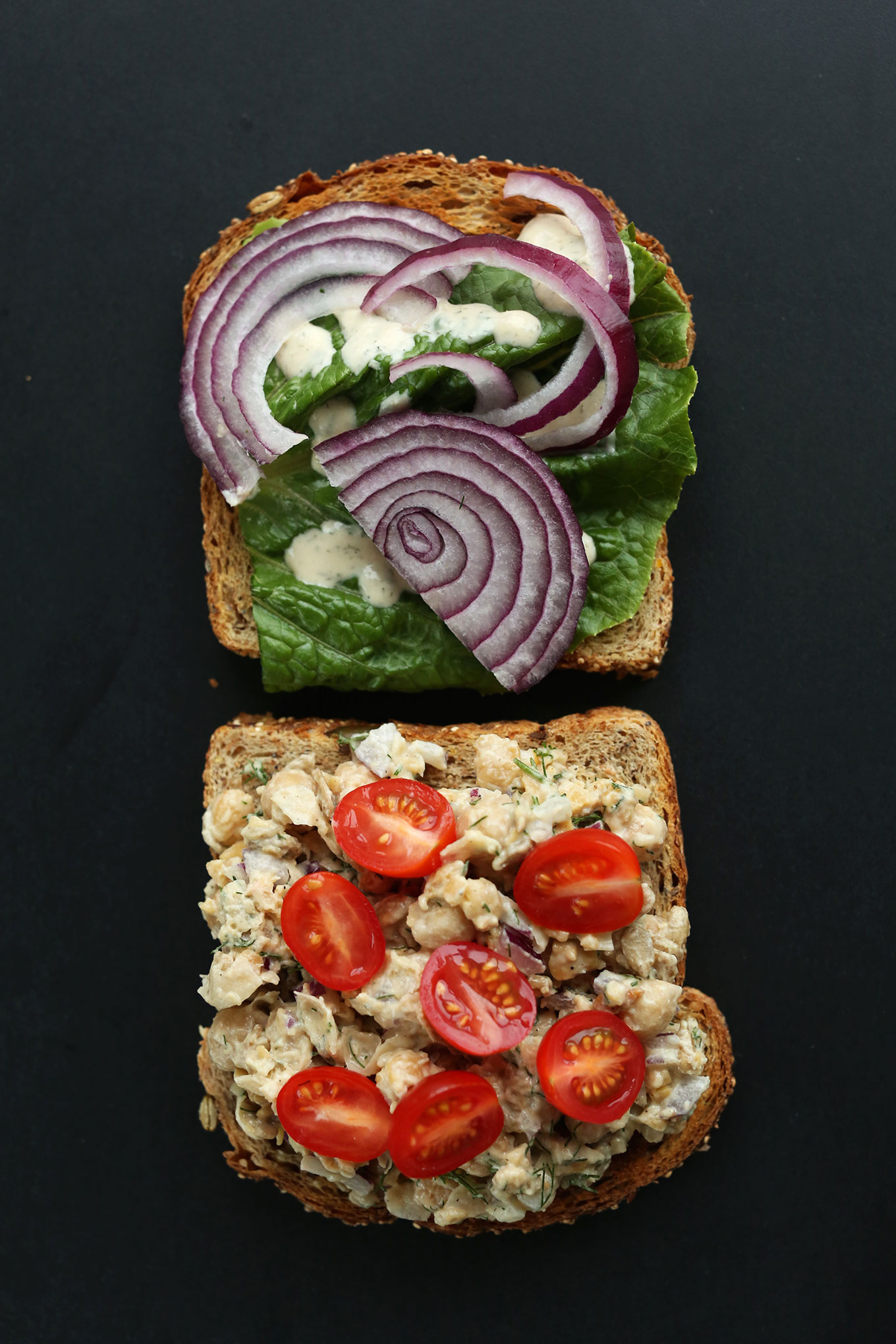 Slices of bread with lettuce, red onion, tomatoes, and Chickpea Sunflower Salad