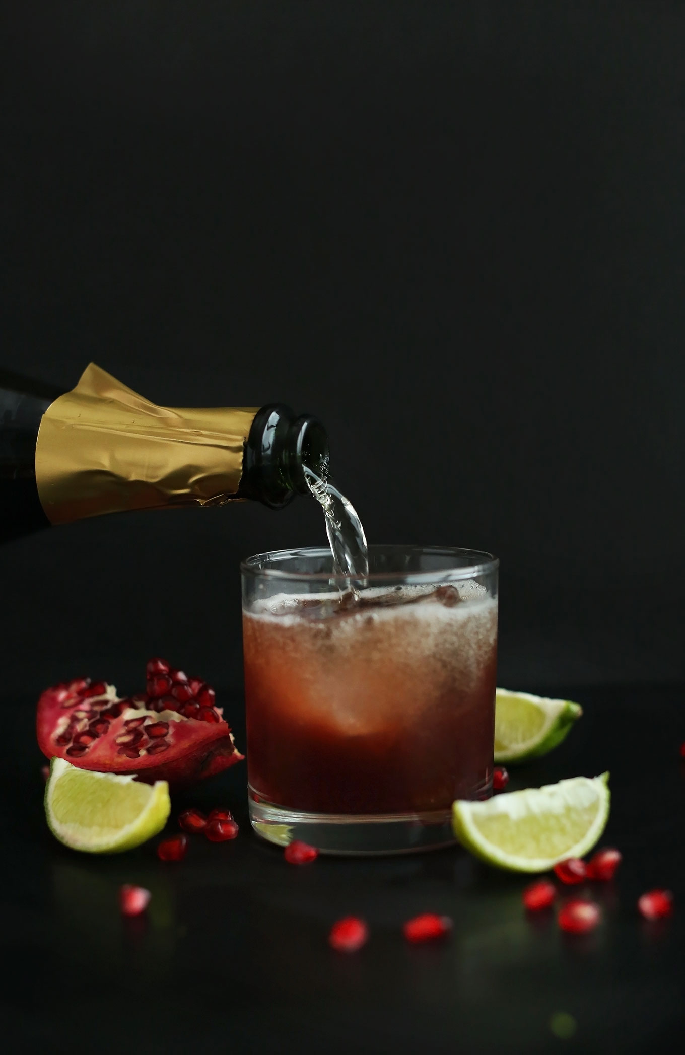 Pouring champagne for New Year's drinks made with pomegranate and lime