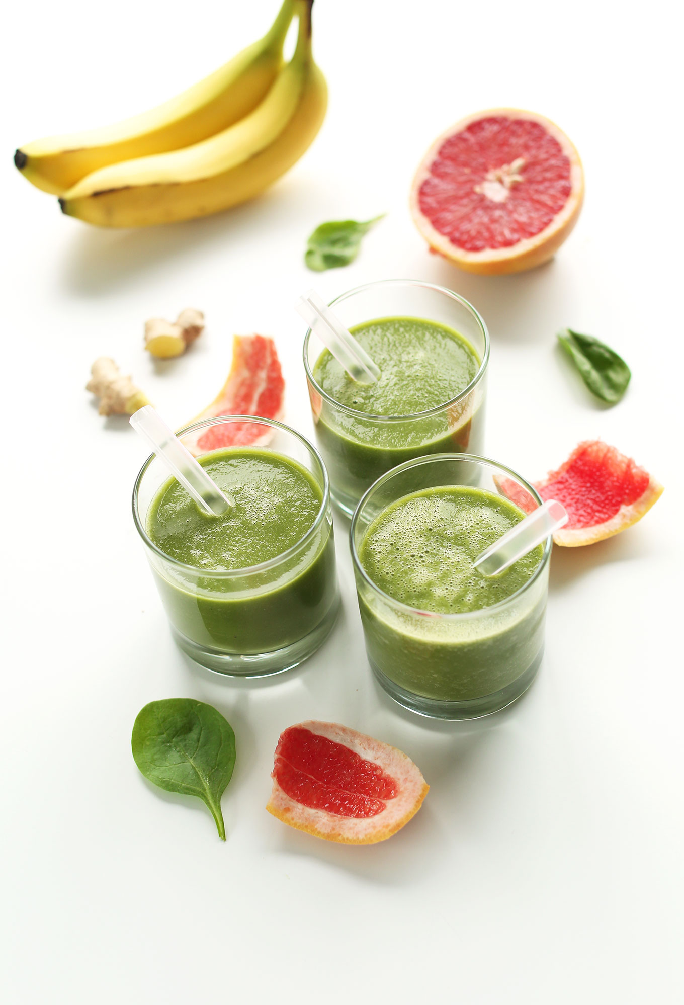 Glasses of our gluten-free vegan Grapefruit Green Smoothie surrounded by ingredients used to make the recipe