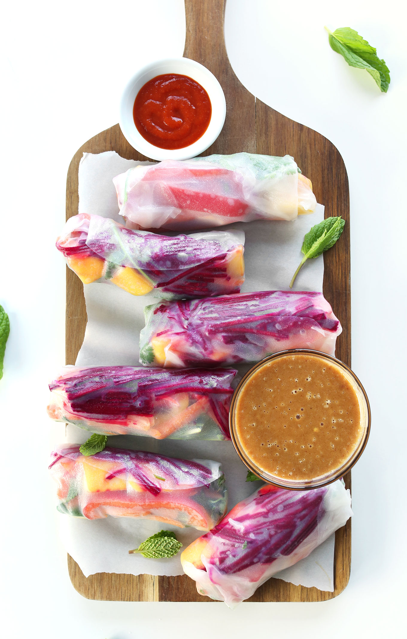 Wood platter filled with vegan Rainbow Spring Rolls and Peanut Sauce