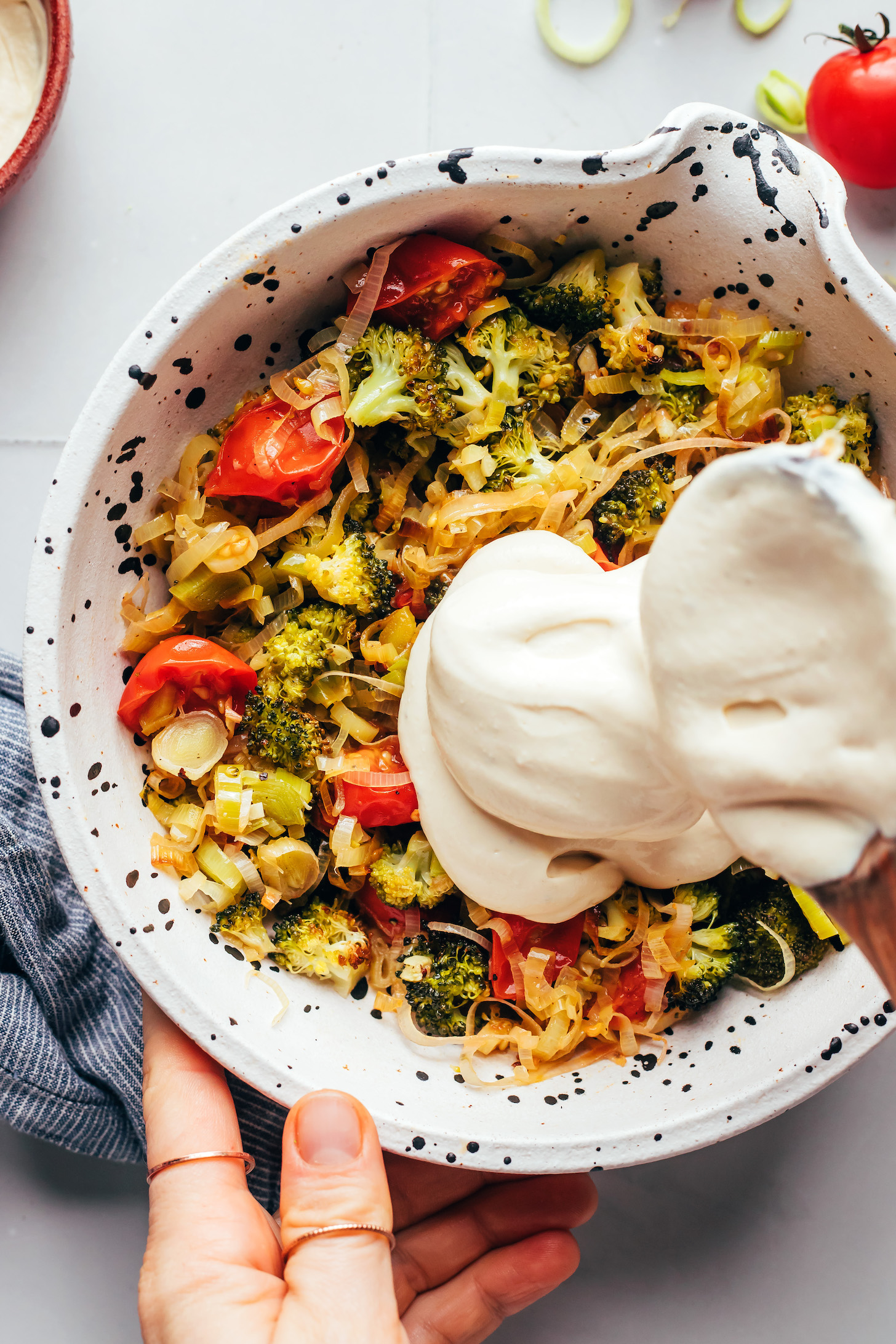Mixing a creamy vegan quiche filling mixture with roasted veggies