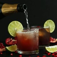Pouring sparkling wine into a glass to make a Sparkling Pomegranate Margarita