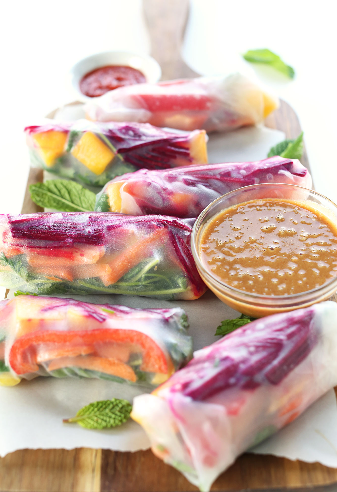 Gluten-free vegan Rainbow Spring Rolls with a bowl of Ginger Peanut Sauce