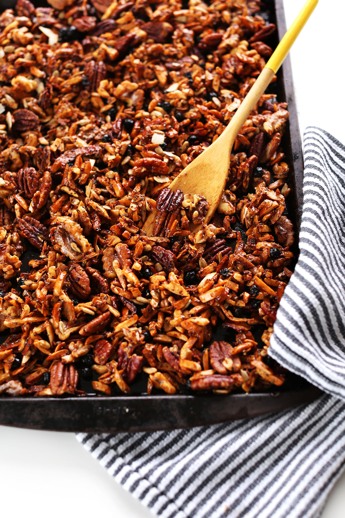 Using a wooden spoon to stir our Grain-Free Granola on a baking sheet