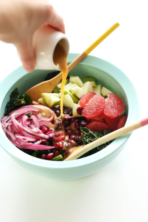 Drizzling homemade red wine vinaigrette onto a big bowl of our Citrus Kale Salad recipe