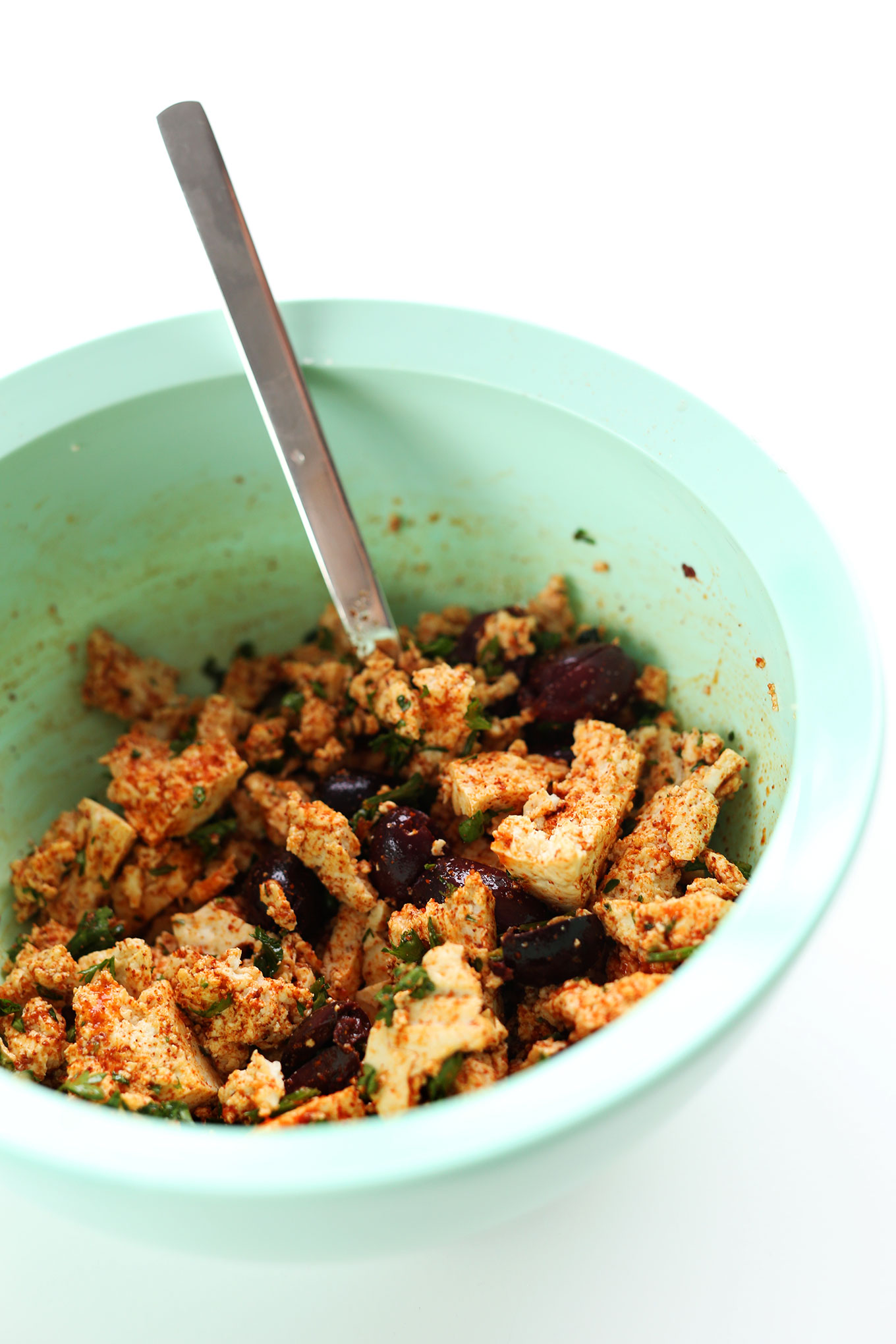 Mixing together tofu, olives, and roasted vegetables for a delicious vegan breakfast recipe