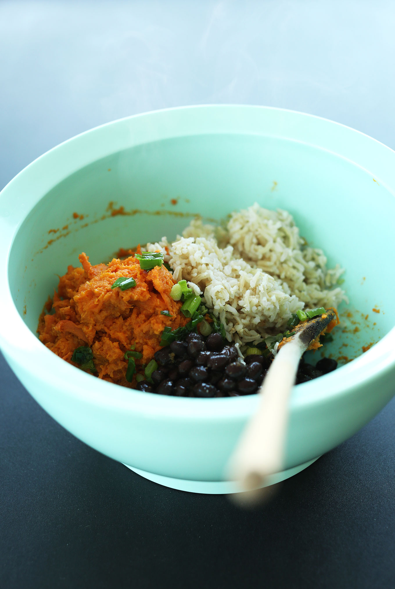 Using a wooden spoon to stir together ingredients for homemade vegan Black Bean Burgers
