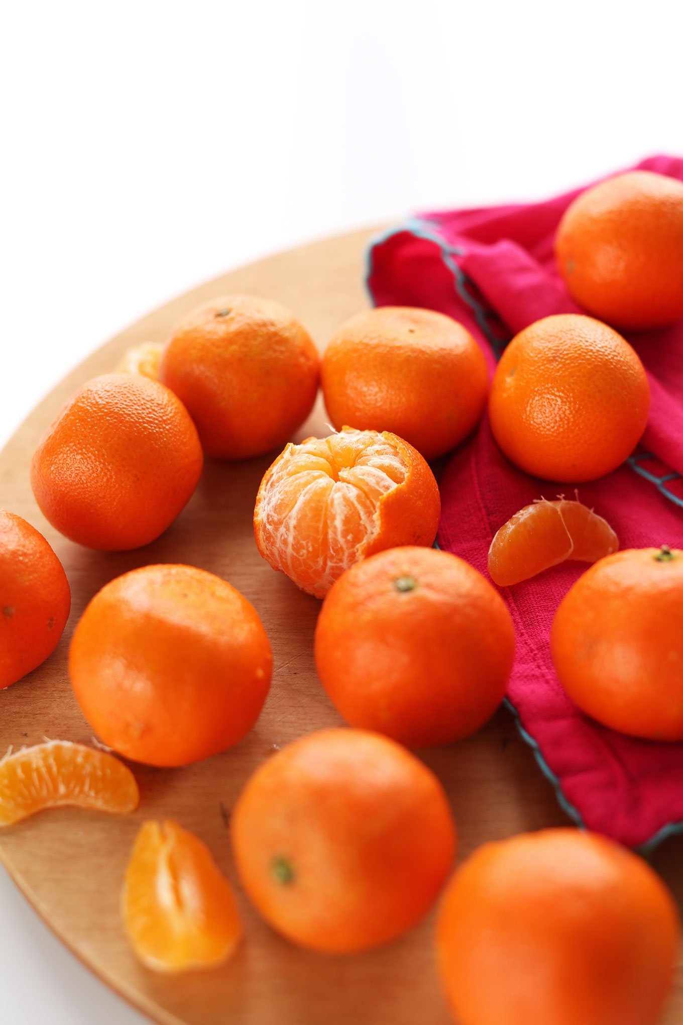 Cutting board filled with fresh clementines for making a vegan green smoothie