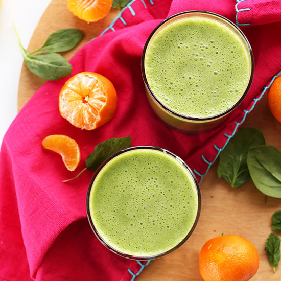 Two glasses of our Coconut Clementine Smoothie recipe beside ingredients to make it
