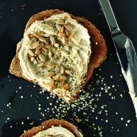 Slices of toast topped with hummus, sunflower seeds, and hemp seeds