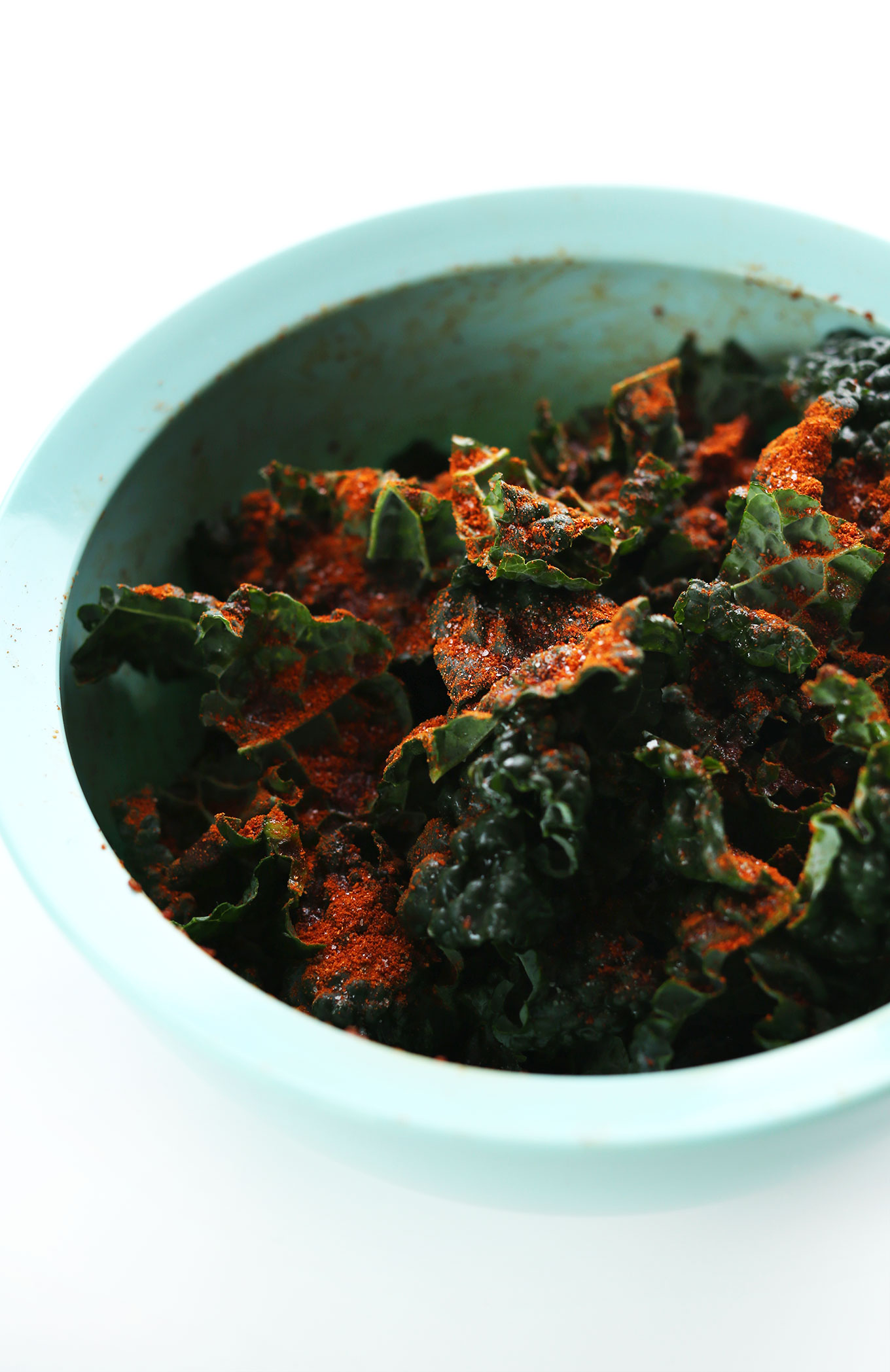 Adding Masala Spice Blend to chopped kale in a mixing bowl
