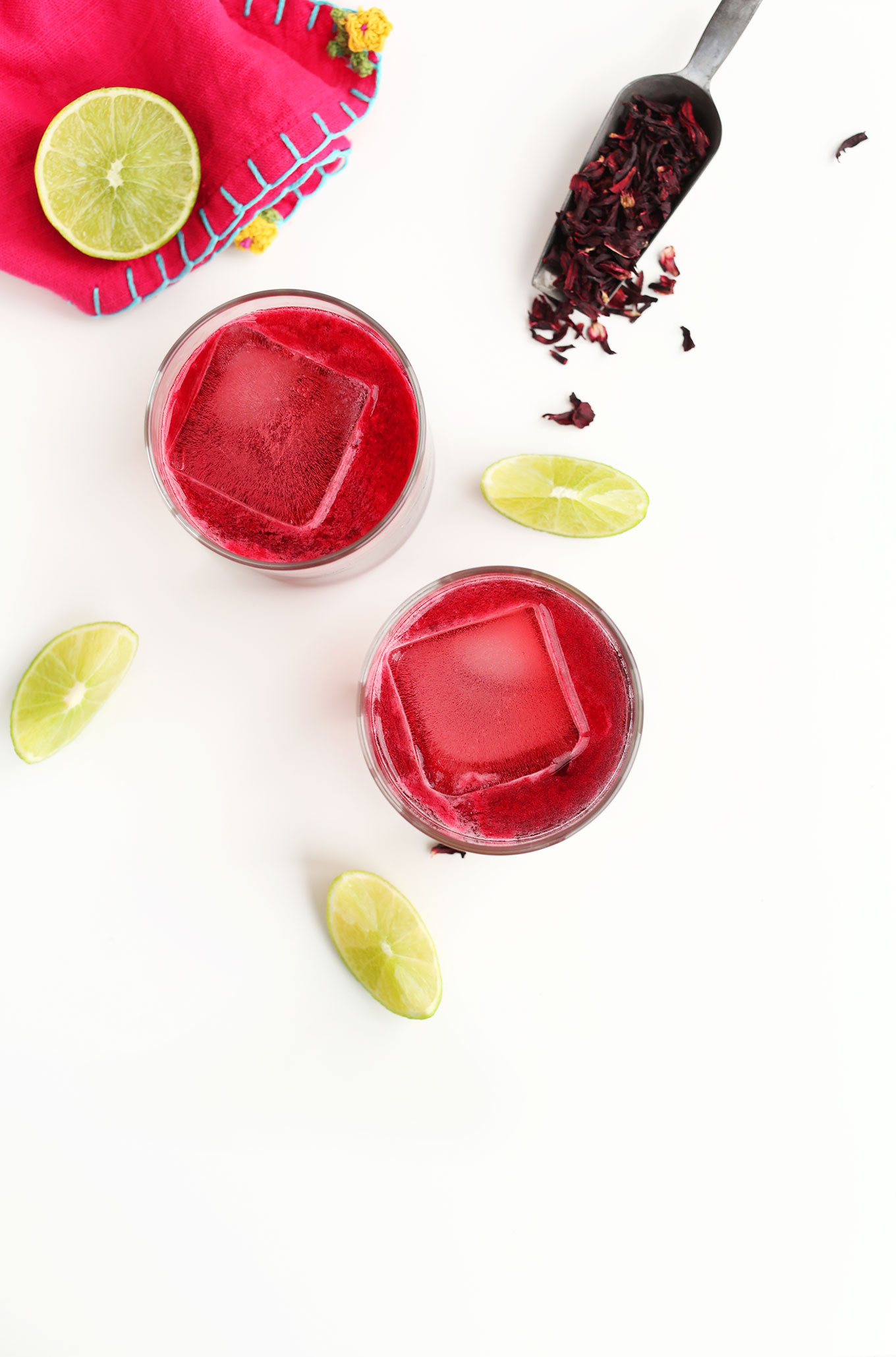 Vibrant pink homemade Hibiscus Margaritas surrounded by lime wedges