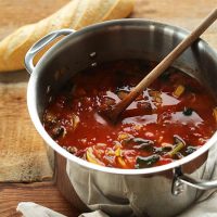 Wooden spoon in a pot of Tomato and Vegetable White Bean Soup