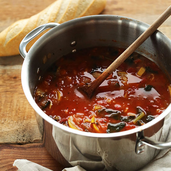 Wooden spoon in a pot of Tomato and Vegetable White Bean Soup