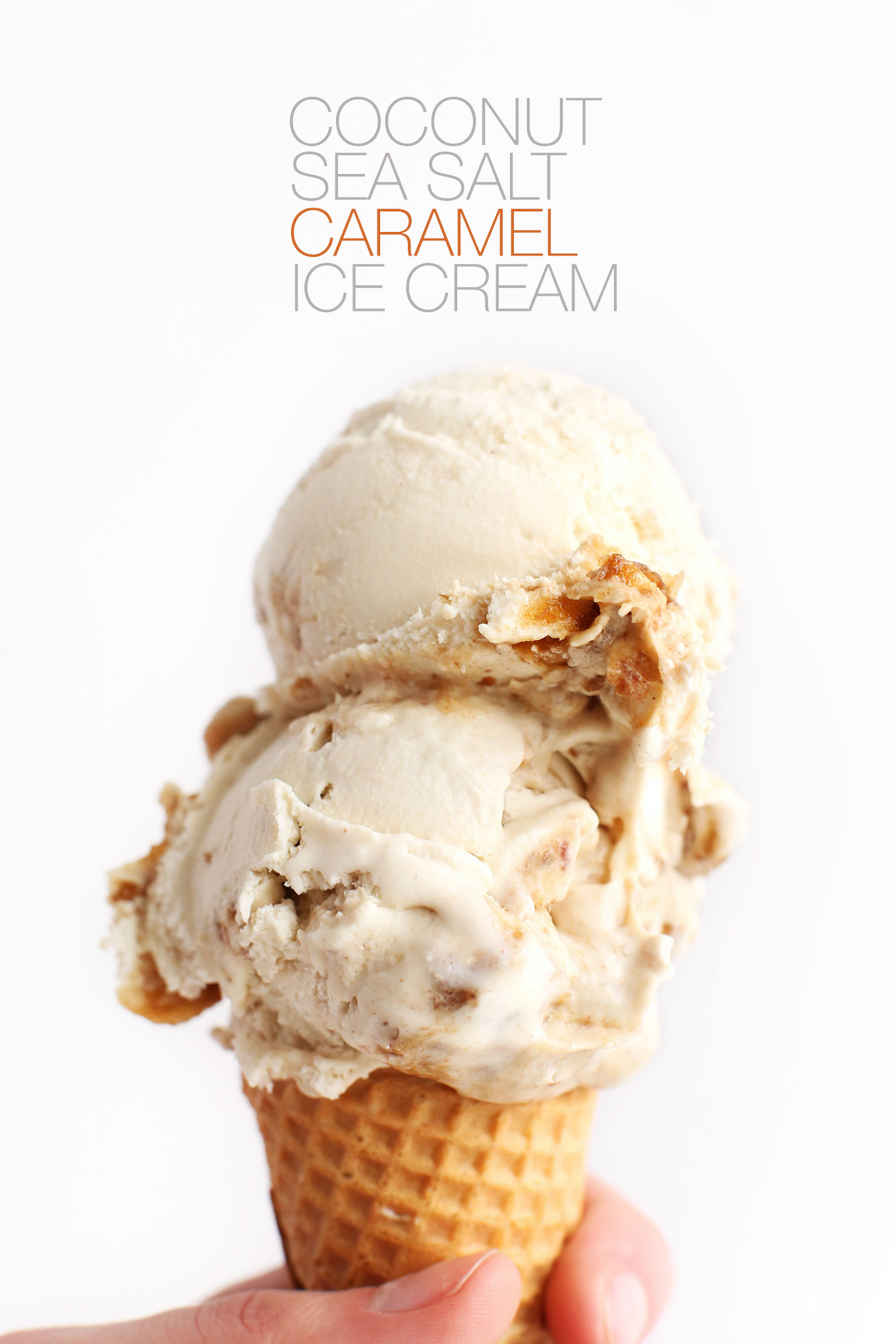 Holding a double scoop ice cream cone of Creamy Vegan Coconut Ice Cream with Sea Salt Caramel