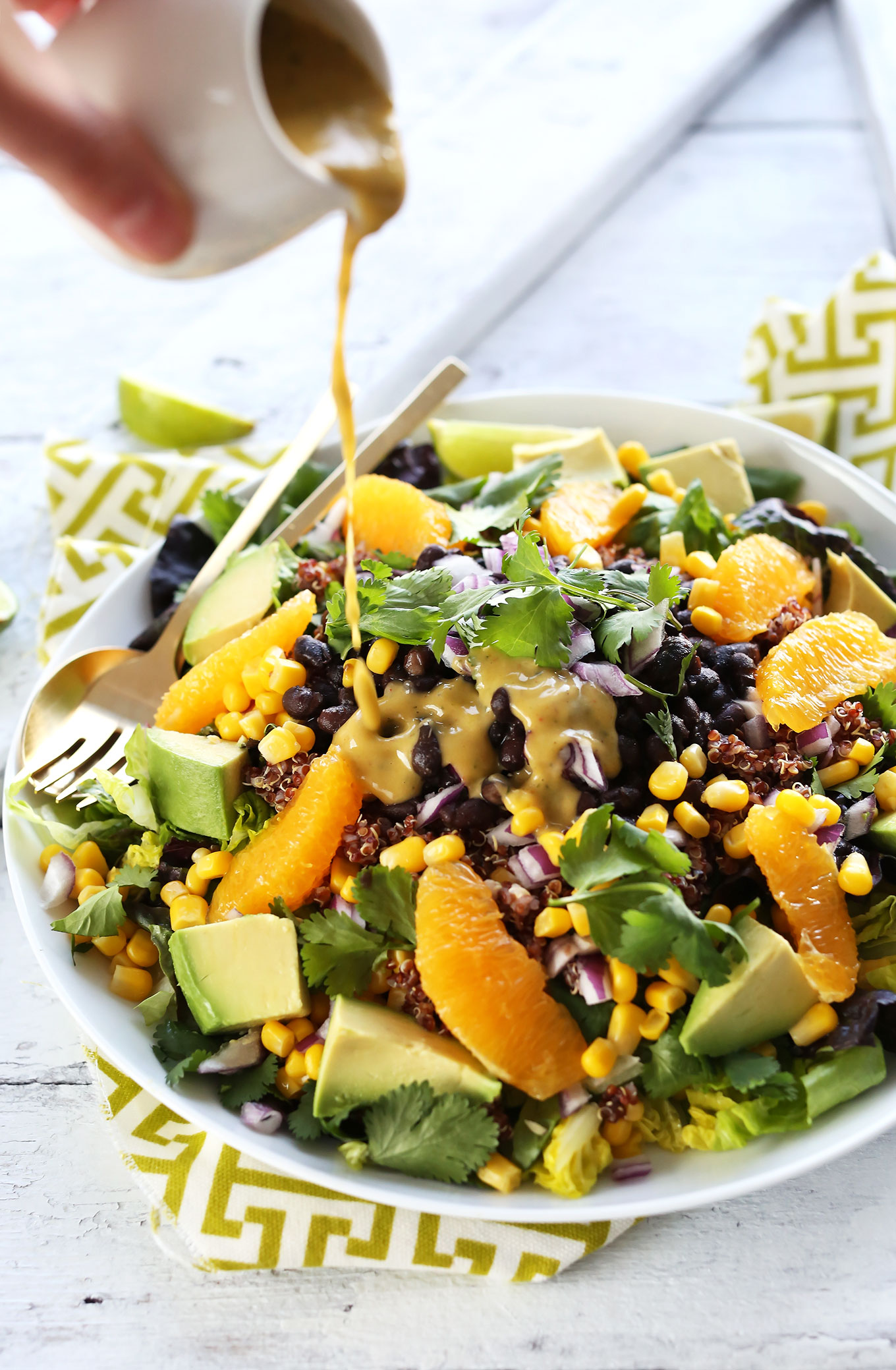 Drizzling Creamy Orange Chili Dressing onto Vegan Mexican Quinoa Salad