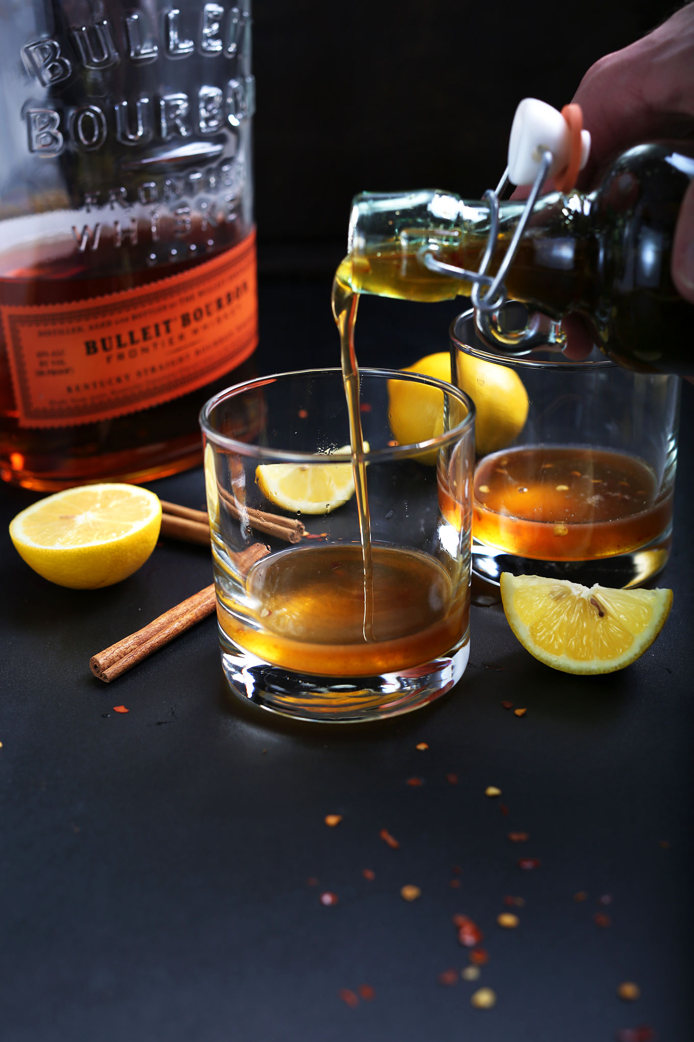Pouring Chili-Infused Maple Simple Syrup into a glass to make Cinnamon Bourbon Hot Toddys