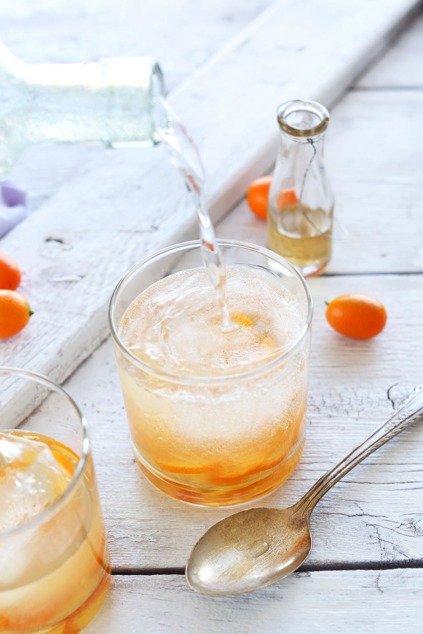 Pouring sparkling water into a glass to make a homemade All Natural Citrus Gin and Tonic