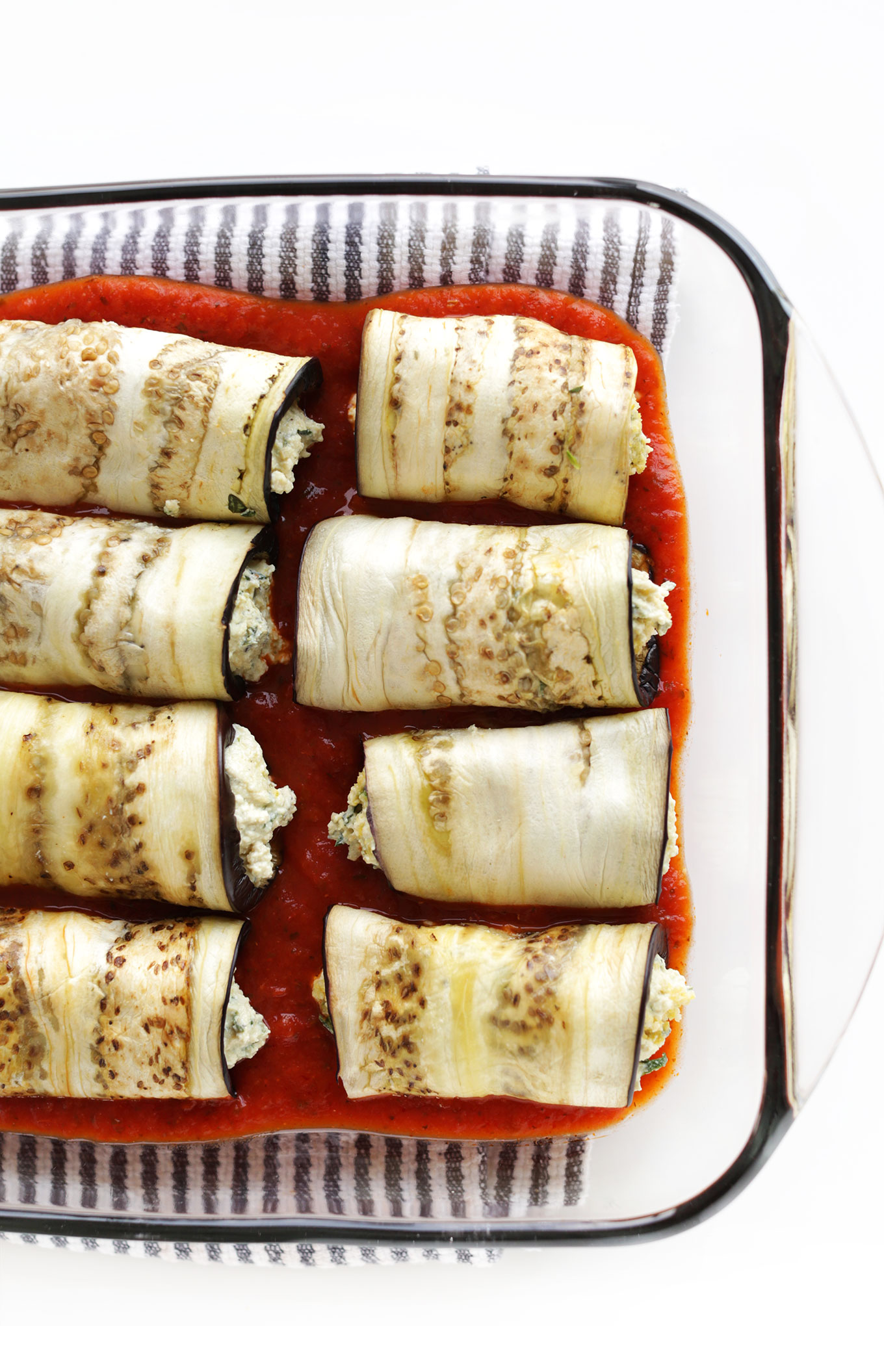 Baking pan with vegan Eggplant Lasagna Roll-Ups resting in marinara sauce