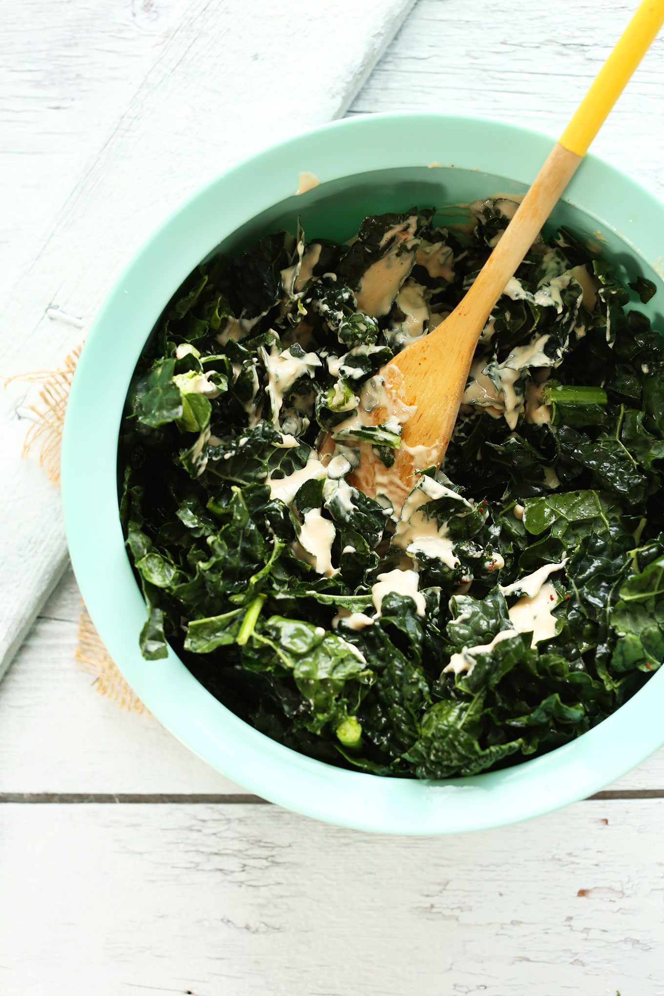 Mixing kale with dressing in a large mixing bowl