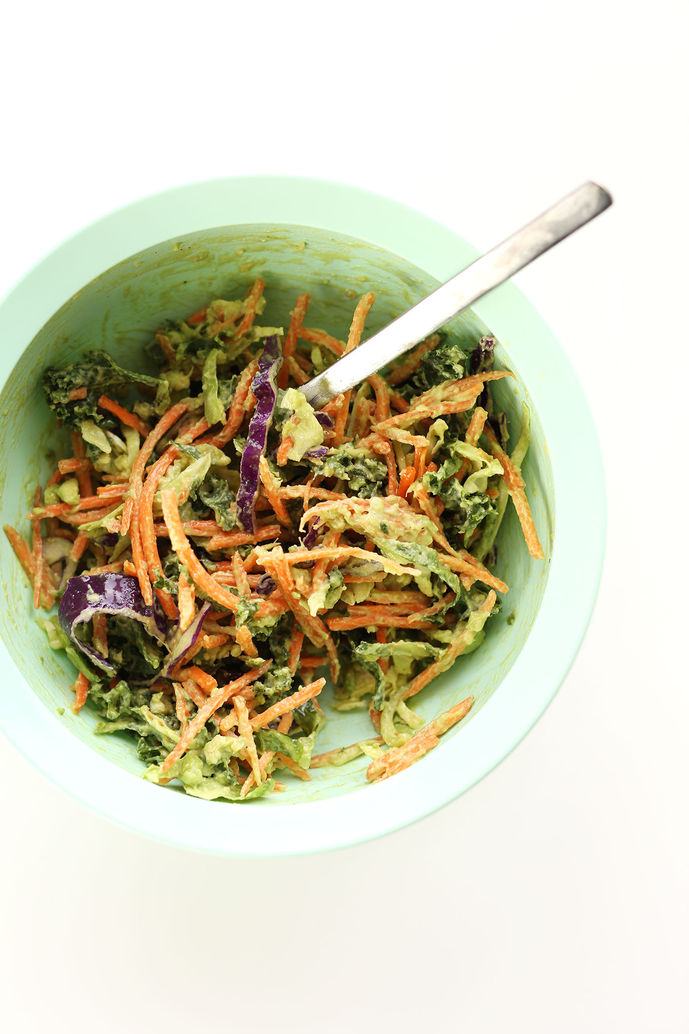 Spoon in a mixing bowl of vegan Avocado Slaw
