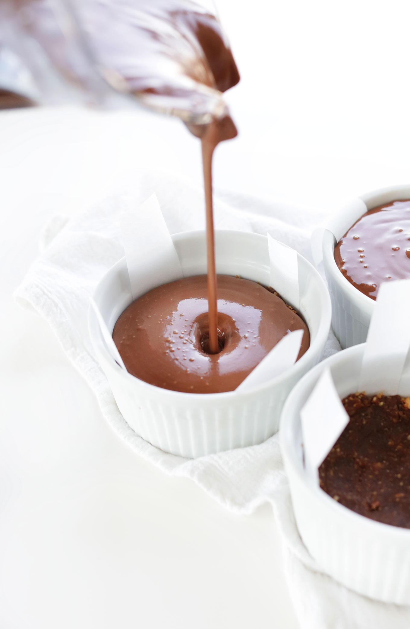 Pouring No-Bake Vegan Chocolate Cheesecake filling into ramekins for a delicious dessert