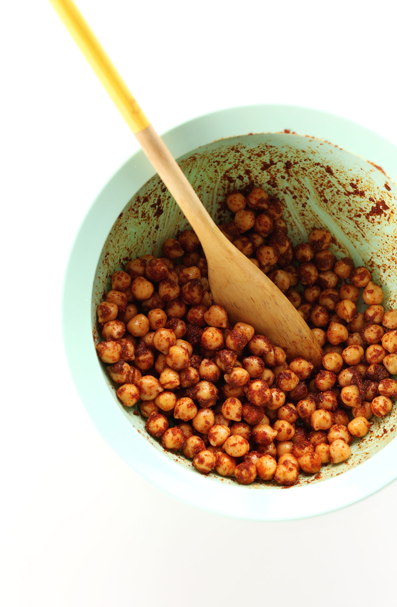 Mixing bowl with spices and chickpeas for adding protein to our vegan salad