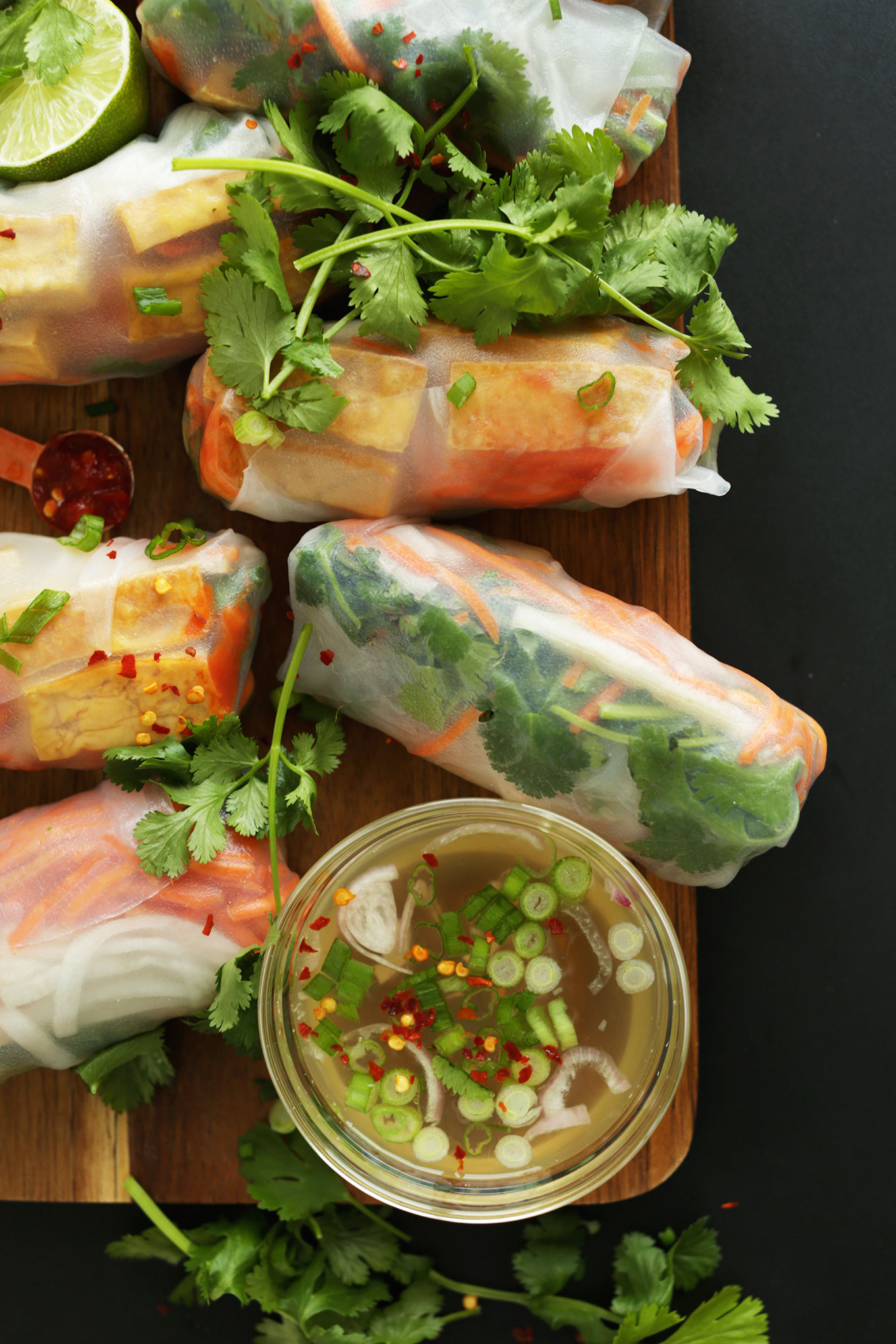 Wood platter of Bahn Mi Spring Rolls and sauce for a fresh vegan meal