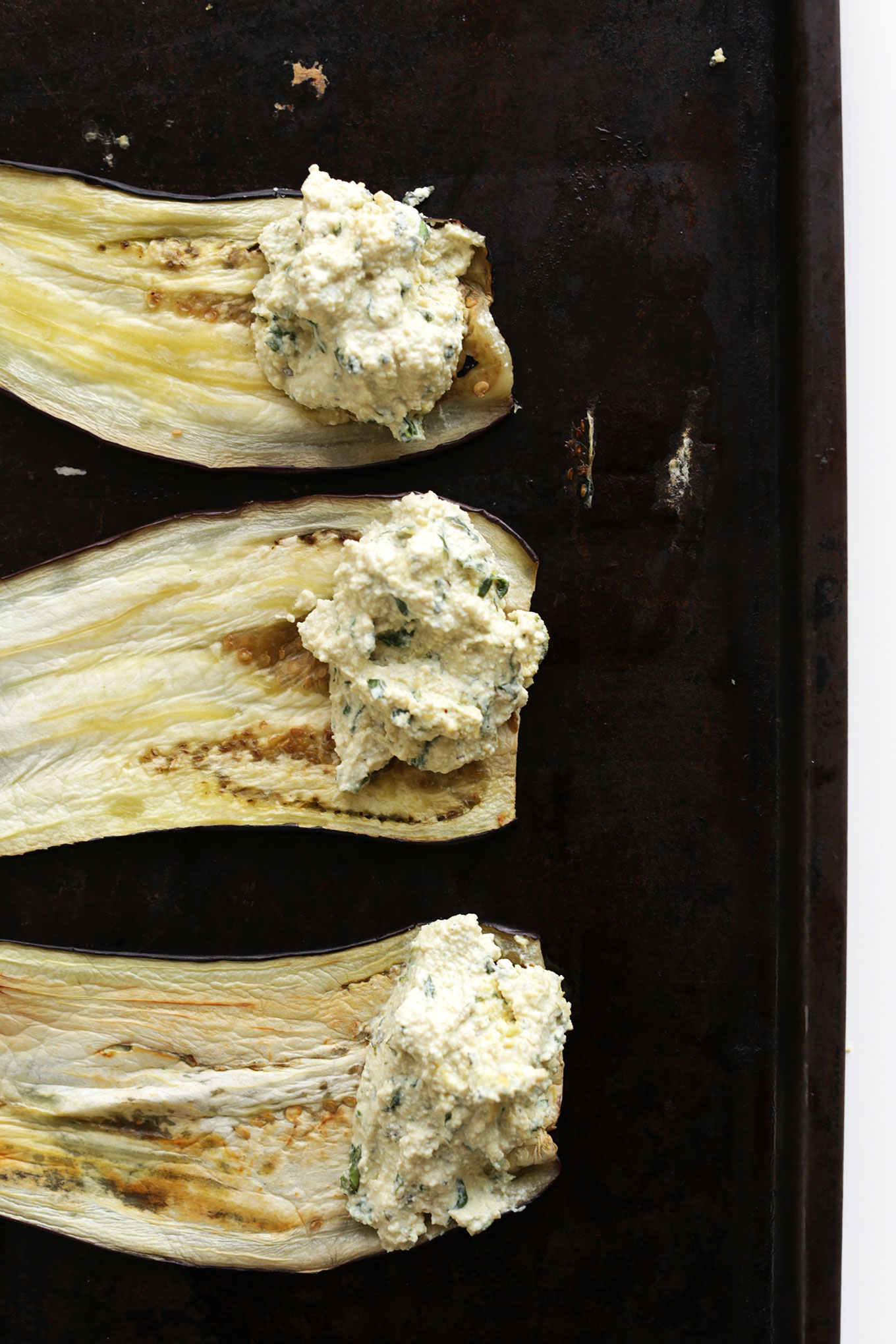 Baking sheet with thinly sliced eggplant with Tofu Ricotta on one end ready to be made into Lasagna Roll-Ups