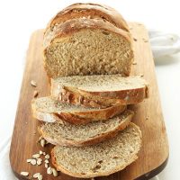 Partially sliced loaf of homemade Whole Grain Vegan Bread on a cutting board