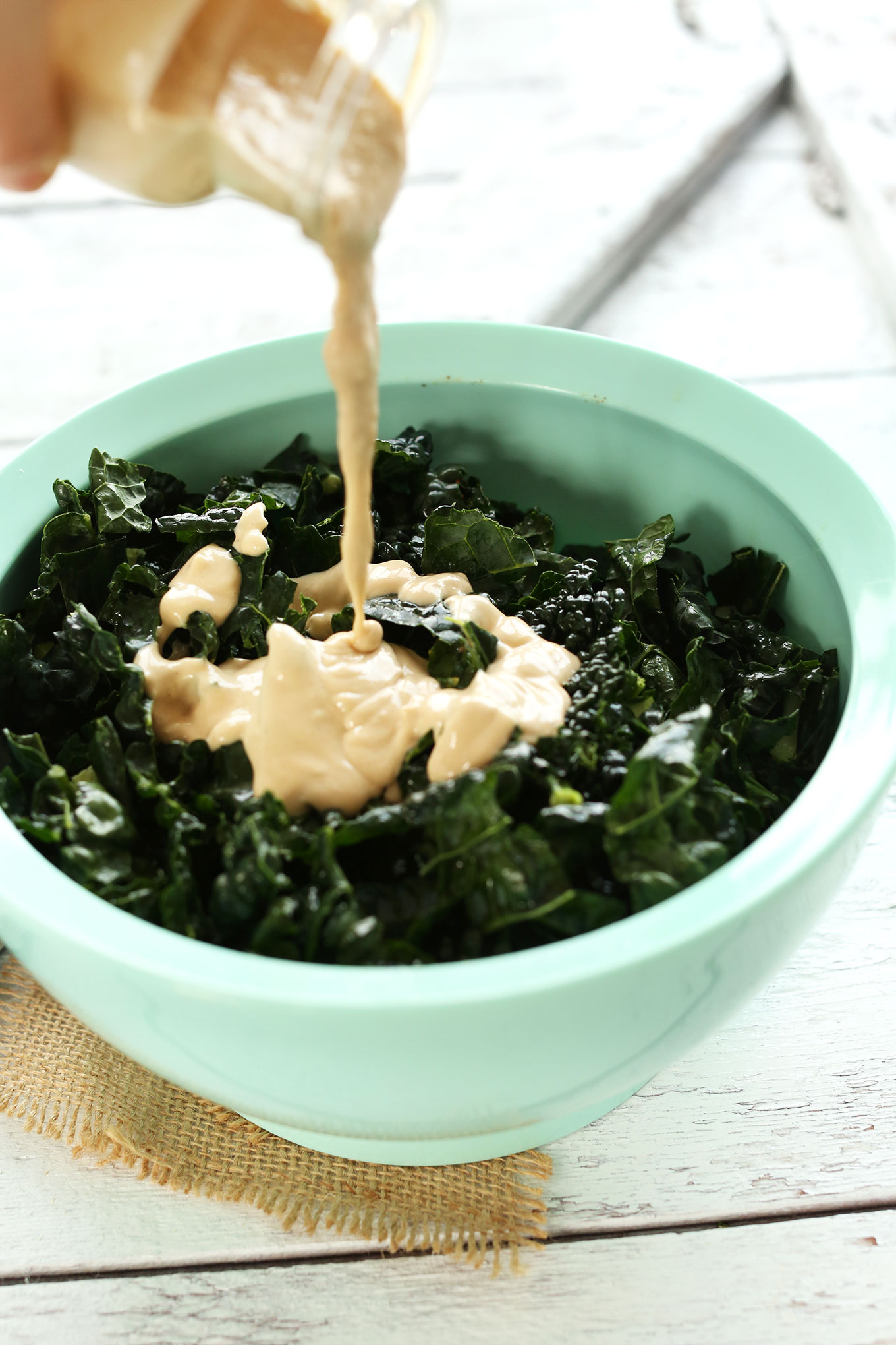 Pouring dressing onto our Garlicky Kale Salad recipe