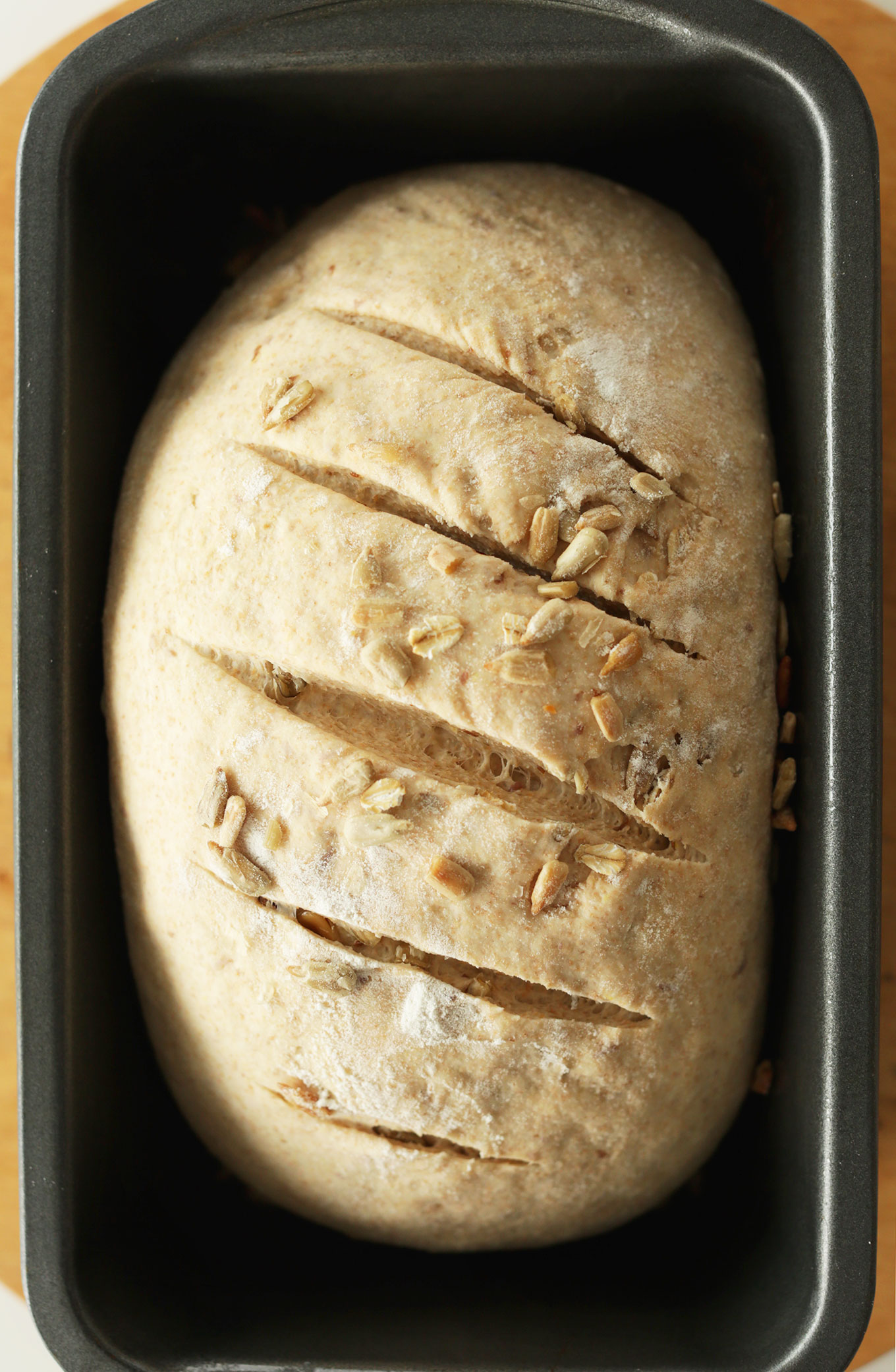 Freshly baked loaf of Whole Grain Seedy Vegan Bread in a bread pan