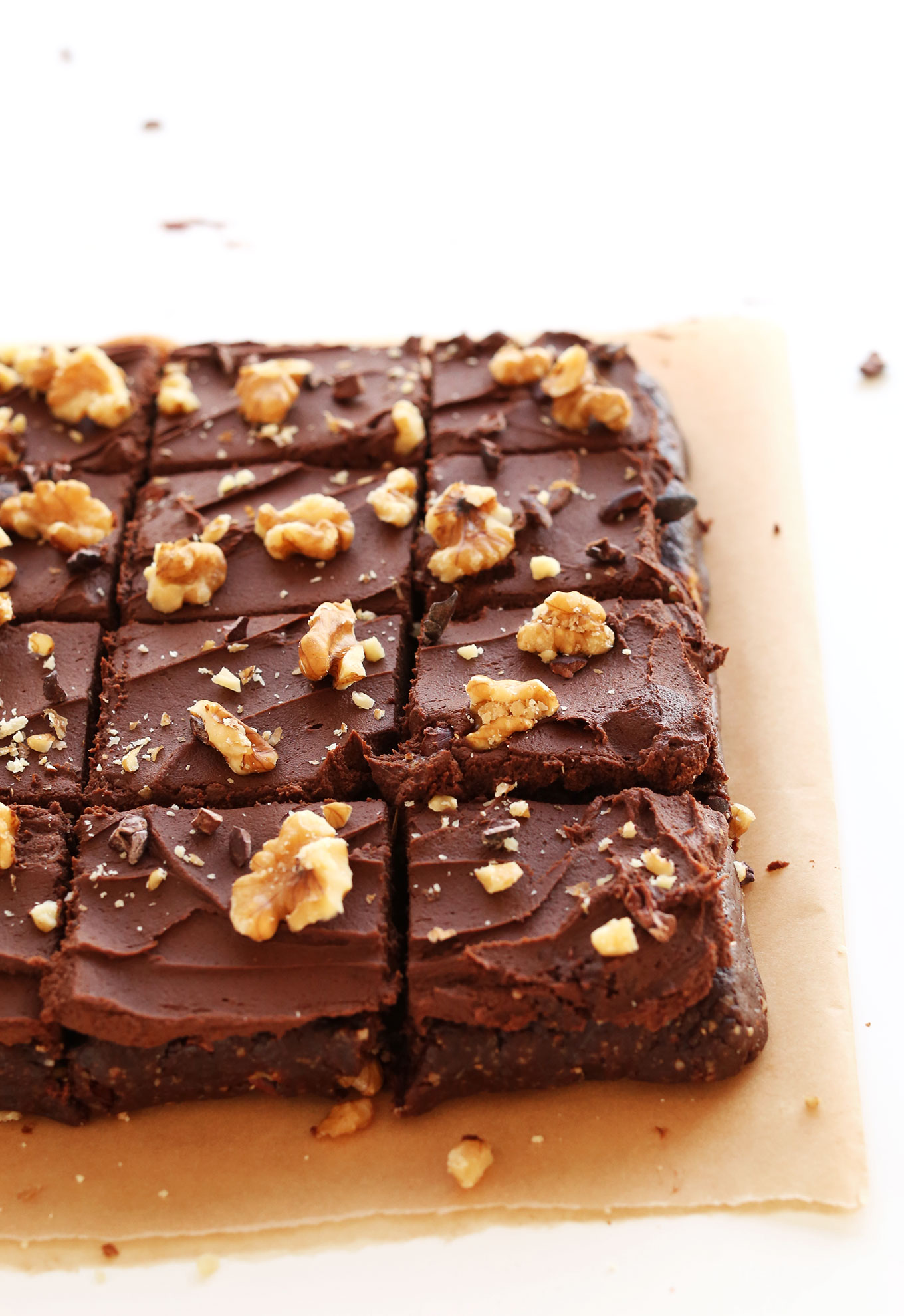 Batch of Raw Vegan Brownies topped with chocolate ganache frosting and chopped walnuts