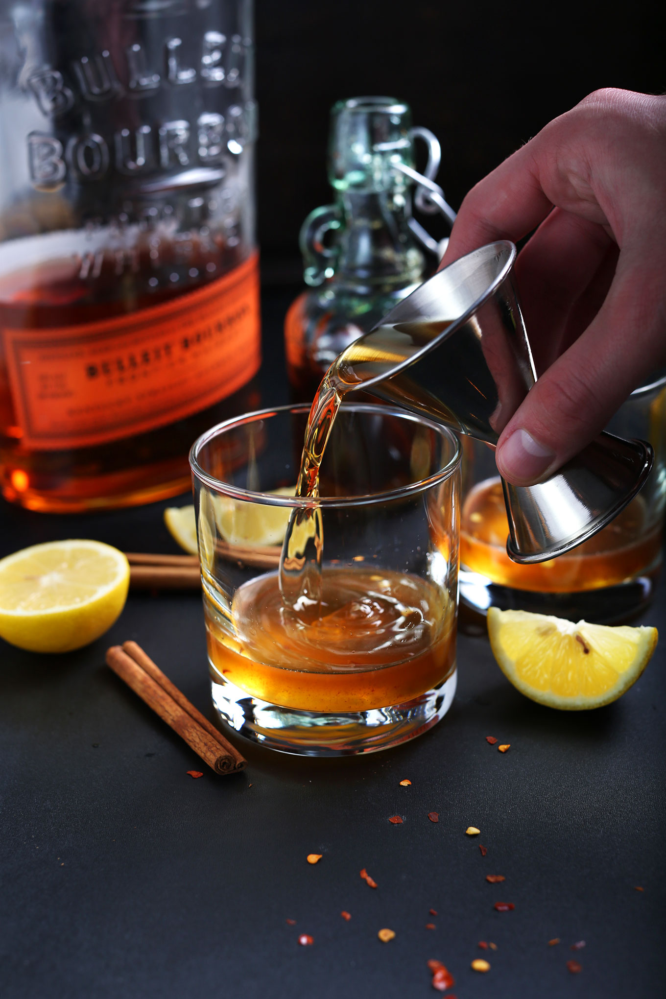 Pouring bourbon into a glass for making a homemade naturally-sweetened Hot Toddy