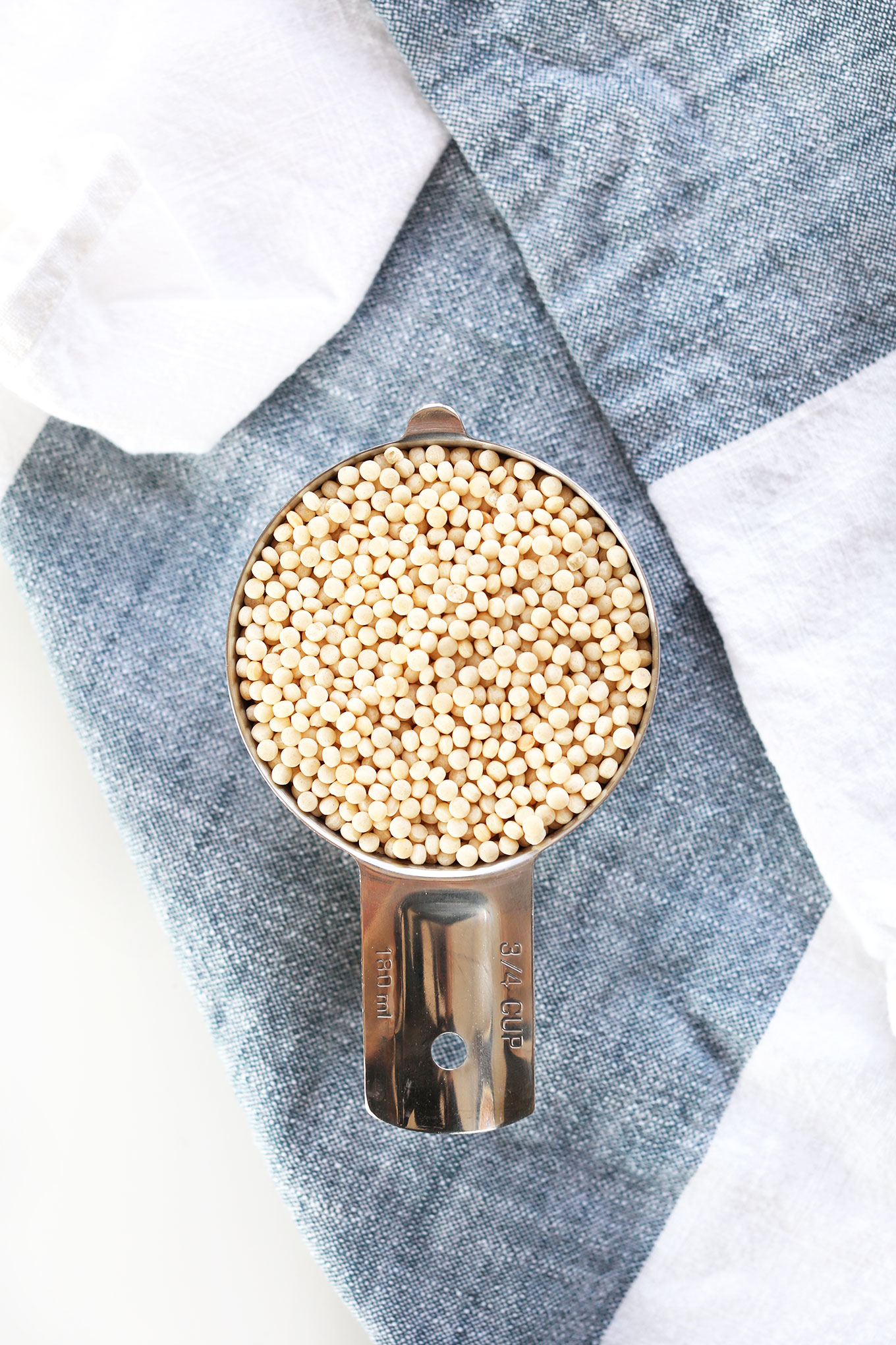 Measuring cup filled with Israeli Couscous for making a quick and flavorful vegan meal