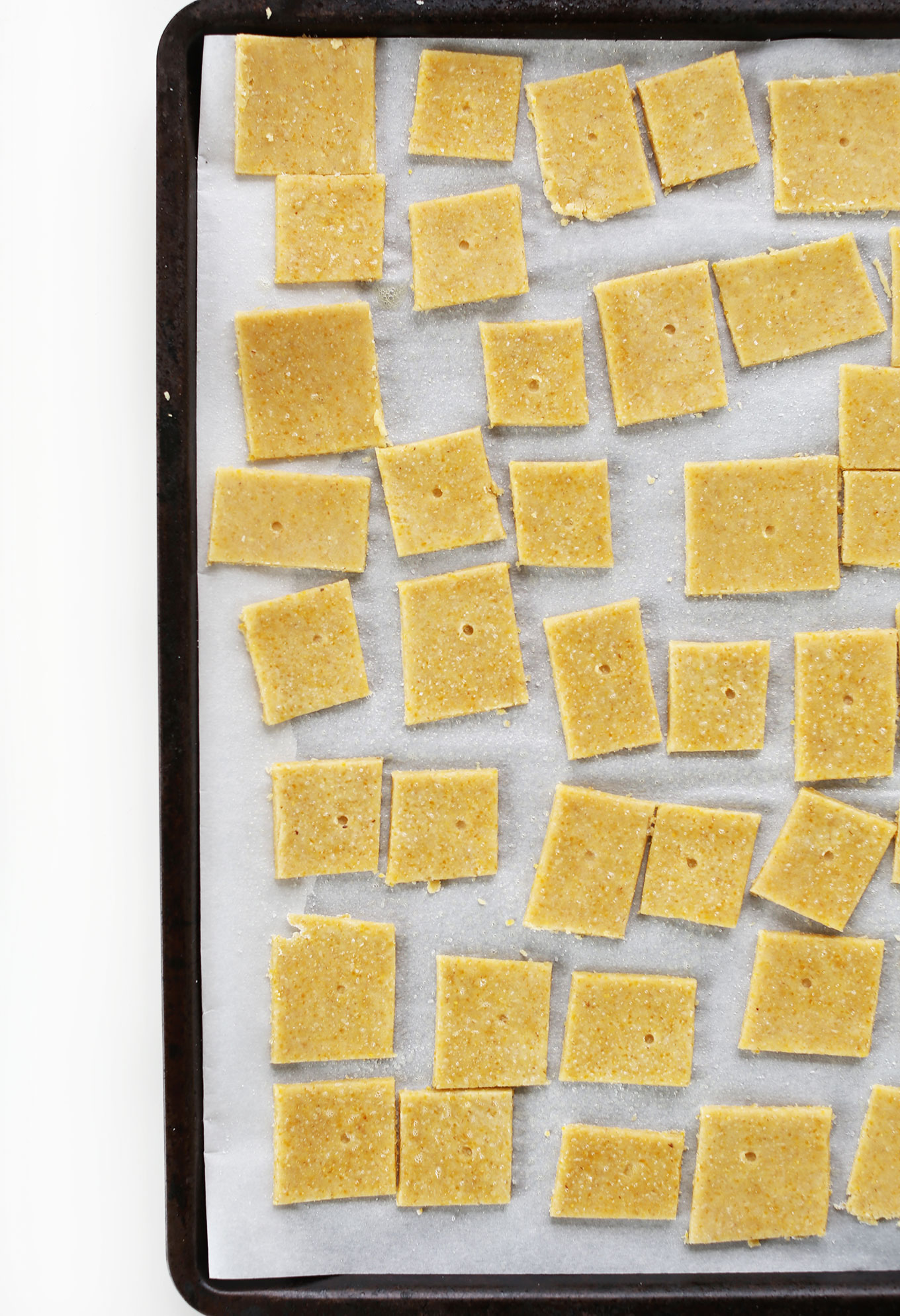 Parchment-lined baking sheet with gluten-free Cheese Crackers ready for baking