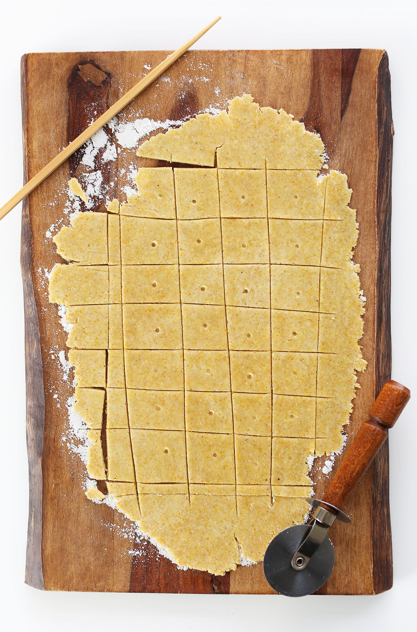 Using a pizza cutter and chopstick to make cuts and dots in our homemade Peanut Butter Cheese Crackers recipe