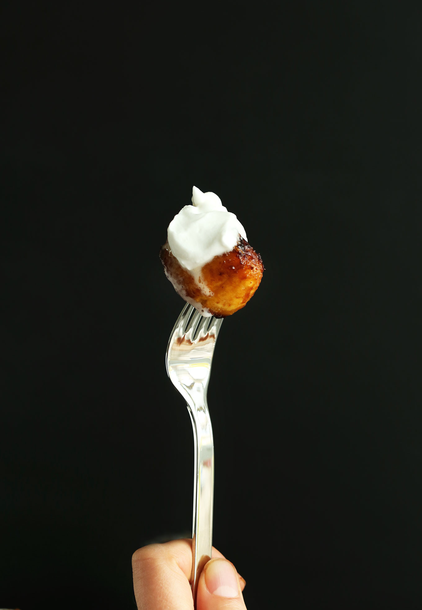 Holding up a Coconut Sugar Caramelized Plantain with coconut whip for a delicious vegan dessert