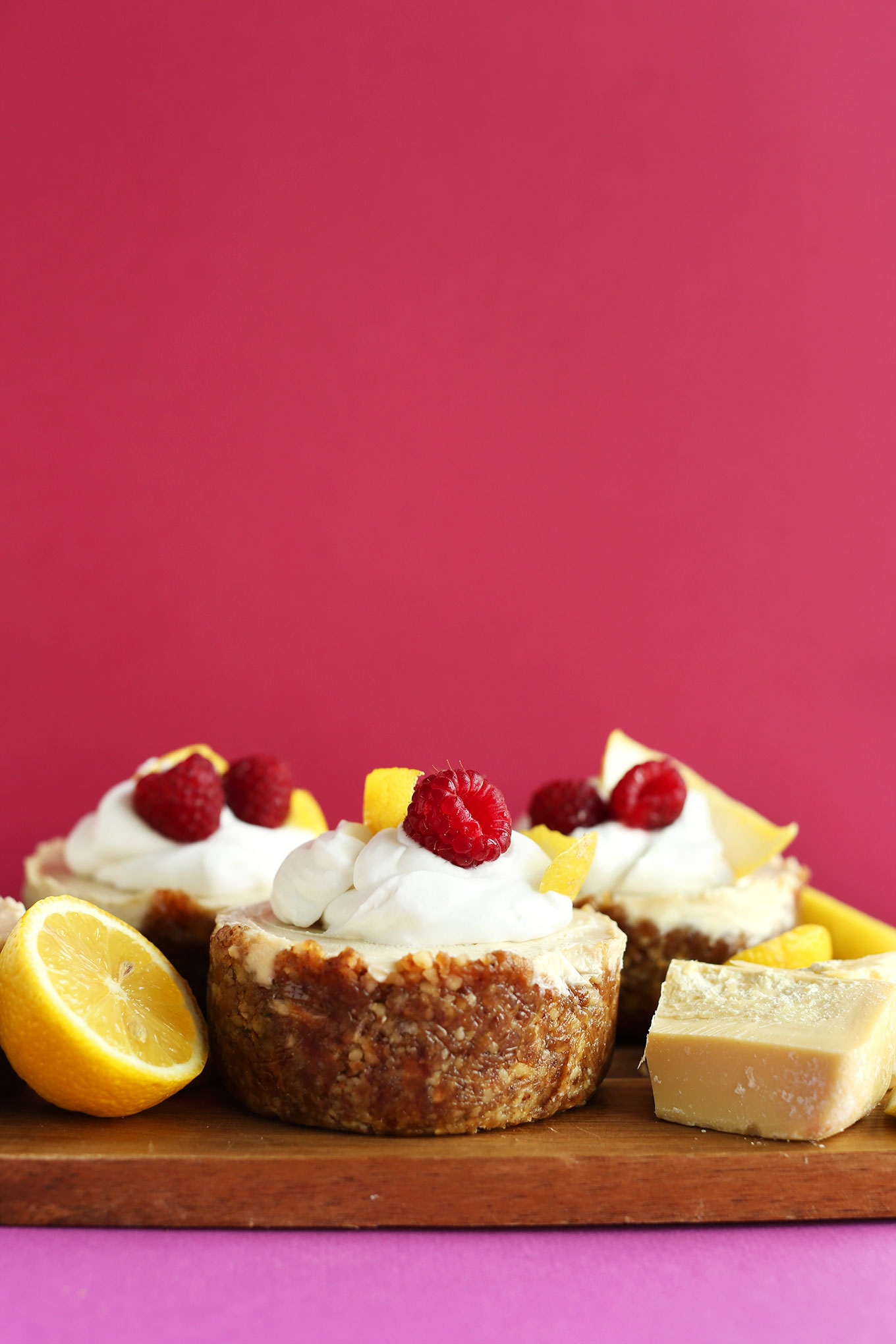 Wood board with mini vegan Lemon White Chocolate Cheesecakes with Walnut-Date Crust