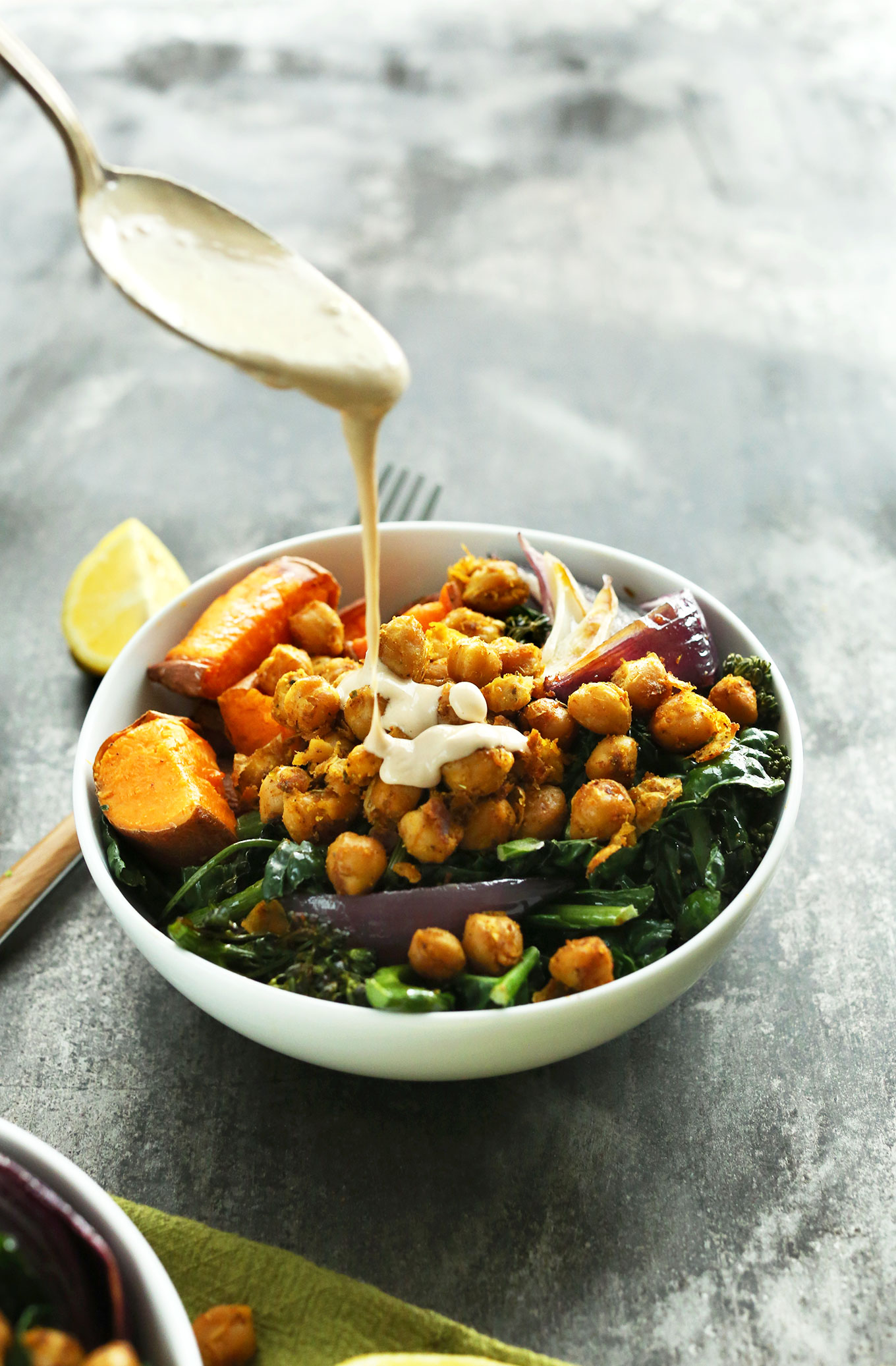 Pouring Tahini Maple Sauce onto a gluten-free vegan Sweet Potato Chickpea Buddha Bowl