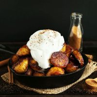 Skillet piled high with Coconut Sugar Caramelized Plantains and coconut whipped cream
