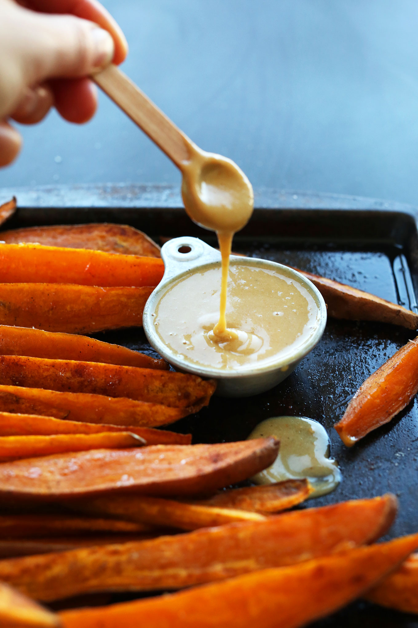 Using a small spoon to drizzle No-Honey Mustard Dipping Sauce for a gluten-free vegan snack