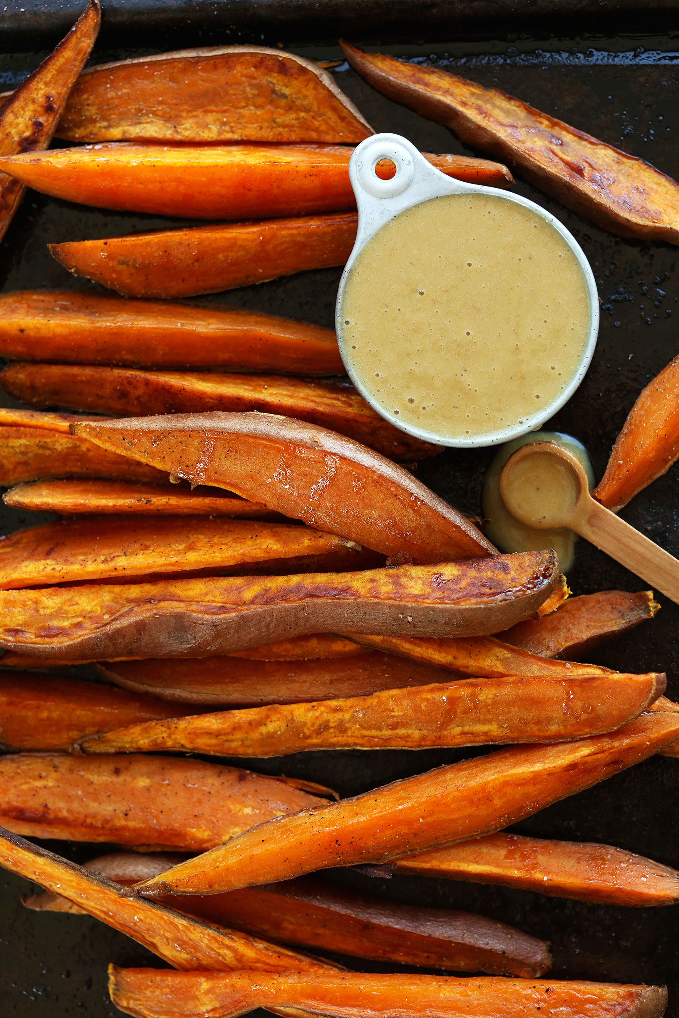 Perfectly browned Savory Sweet Potato Wedges with a side of vegan No-Honey Mustard Dipping Sauce